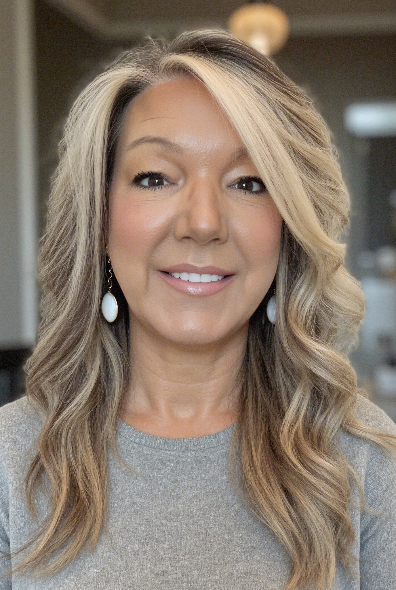 Elegant woman with wavy hair wearing pearl earrings, showcasing luxury artisan jewelry.